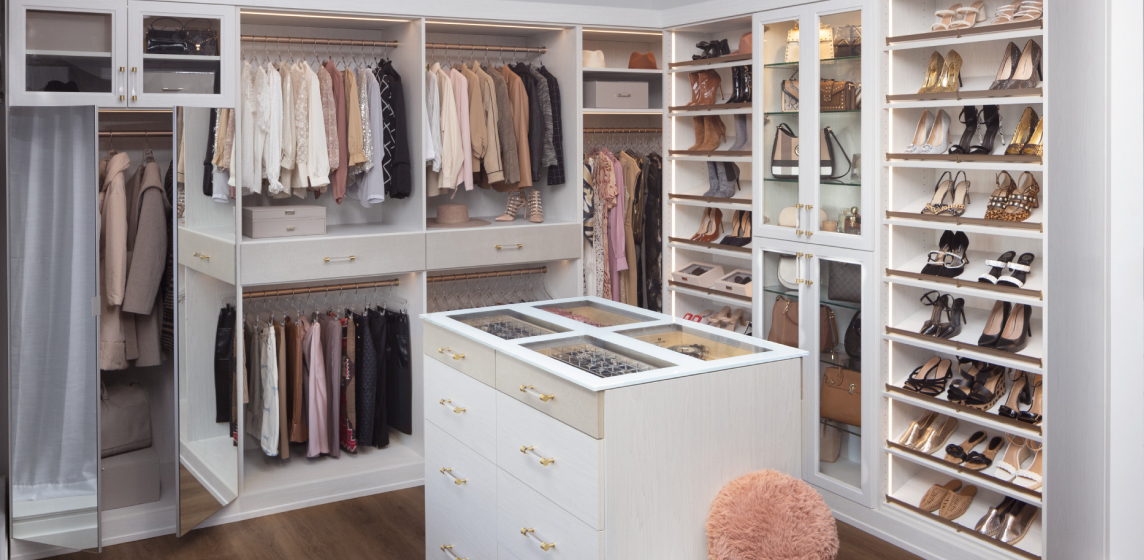 A highly designed closet with white shelving and drawers neatly showcasing clothing.